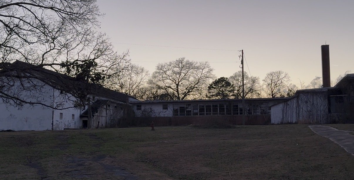 The campus, wide view of the long central wing and gymnasium at dusk
